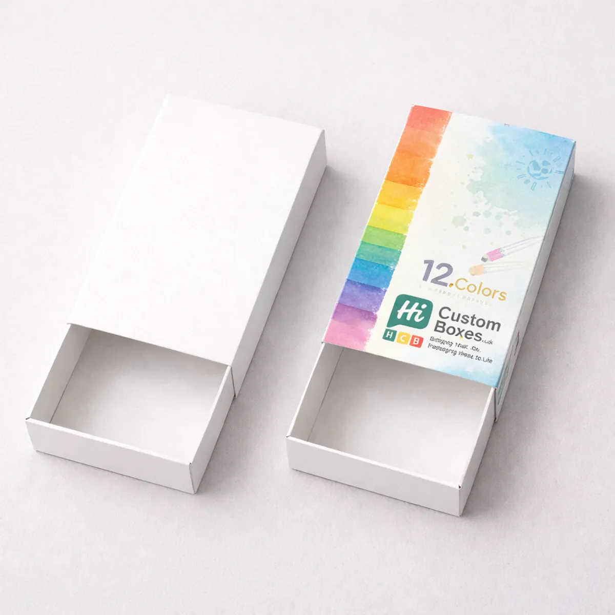 Two sliding drawer-style pencil boxes; one is plain white and the other shows a 12-colour rainbow and paint effect. class=